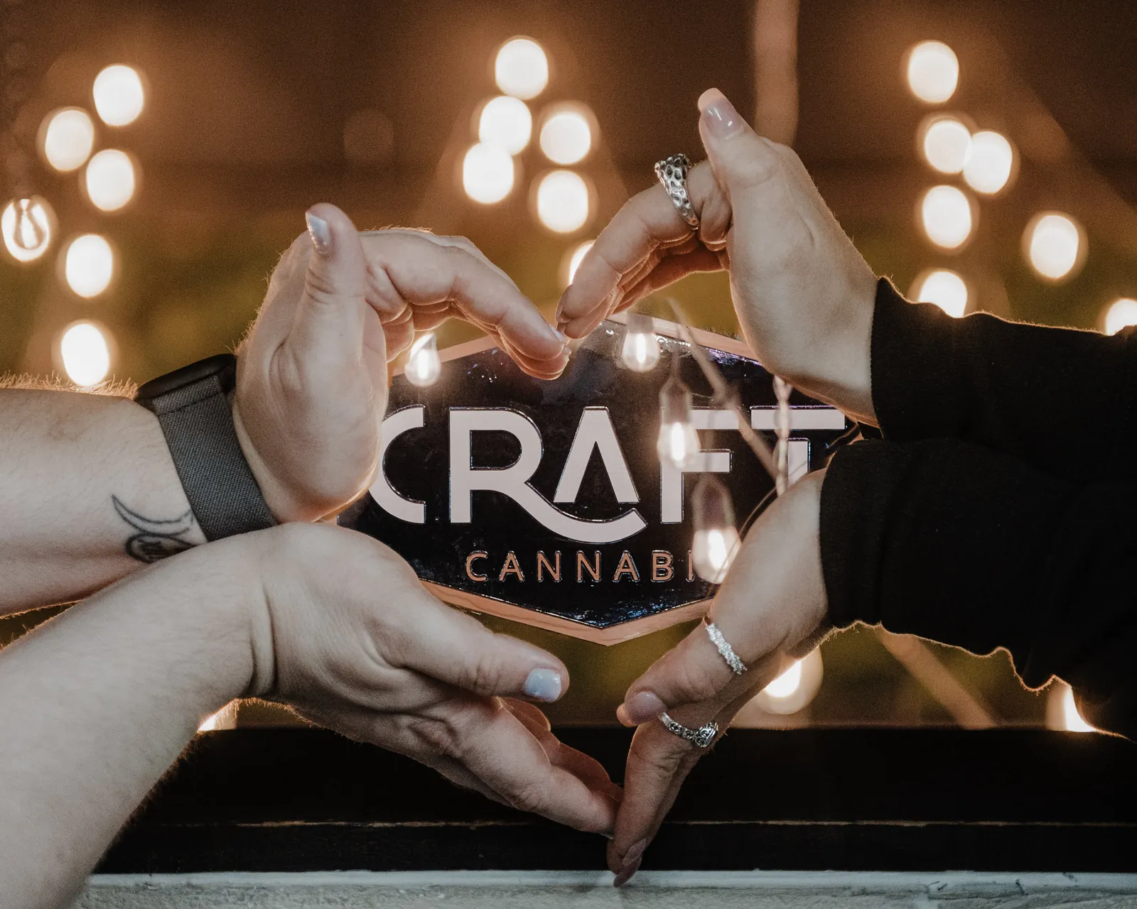 Two hands making a heart around the Craft Cannabis logo